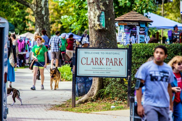 Clark Park sign in between people walking.